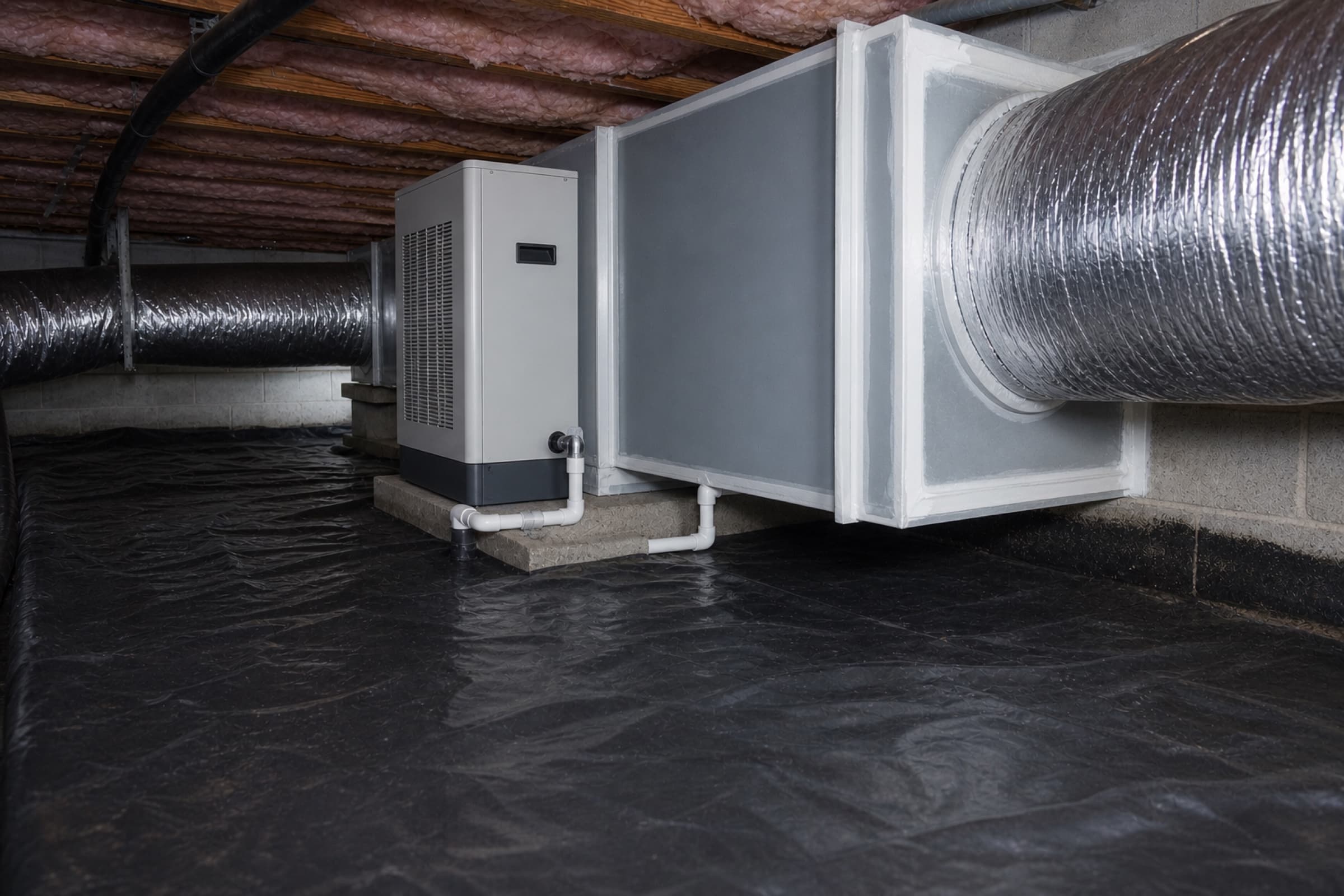 A whole-home dehumidifier installed beside the air handler with a new sealed plenum and condensate line